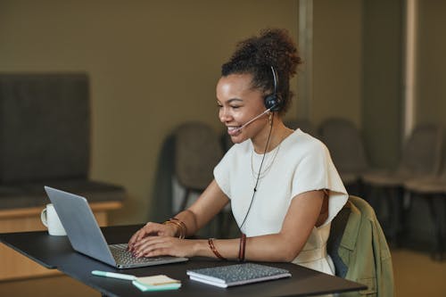 Smiling Information Technology professional wearing a headset working on a laptop in a modern office