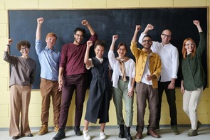 Eight early-career professionals stand united in front of a blackboard, raising fists in celebration—symbolizing the leadership, agility, and career momentum gained through a Master’s in Management (MSM)