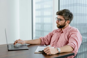 Professional in a modern office reviewing data on a laptop and clipboard, representing career opportunities in criminology and justice studies.