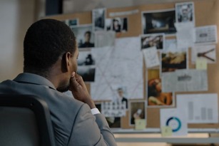 Investigator studying an evidence board of photos, maps and notes, reflecting the analytical work in criminology and criminal justice careers